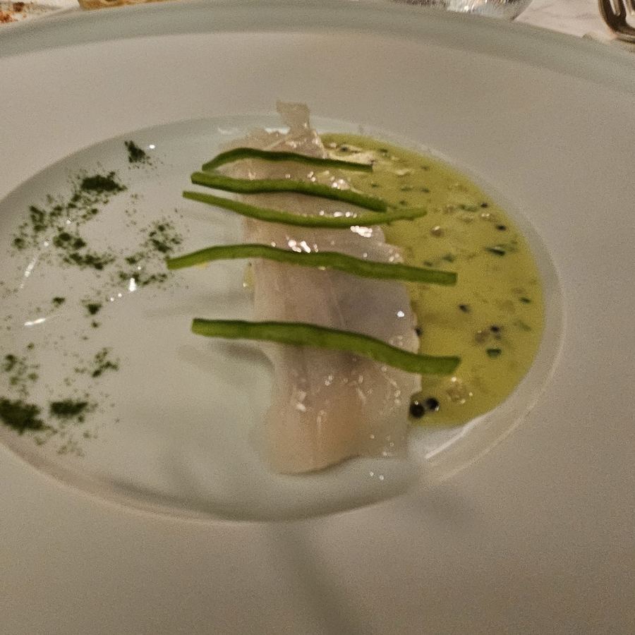 Teller mit Fisch in einem grünen Olivenölsud